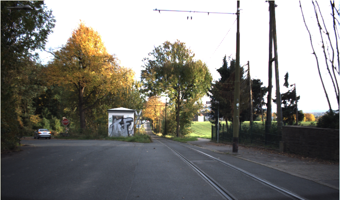 Straße von Bäumen umgeben und Stoppschild in weiterer Entfernung (schlecht aufgrund der Begrünung) erkennbar.